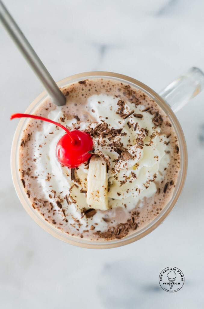 top down view of a milkshake topped with whipped cream and a cherry