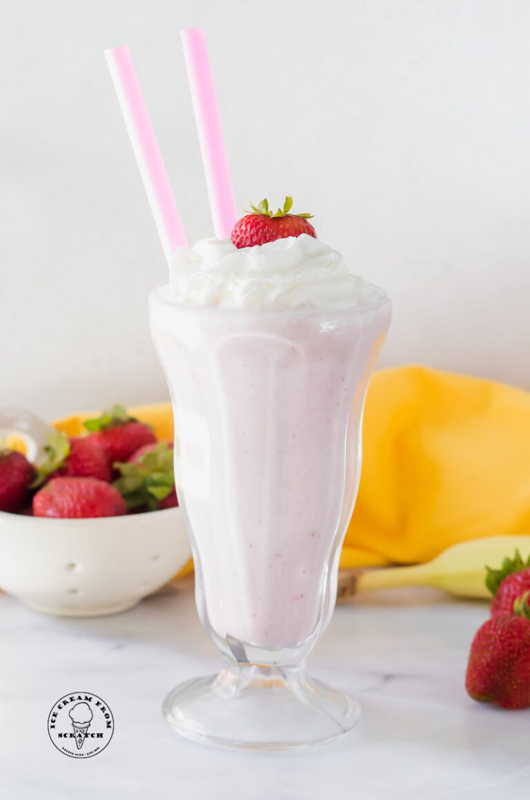 strawberry banana milkshake in a tall glass with two straws