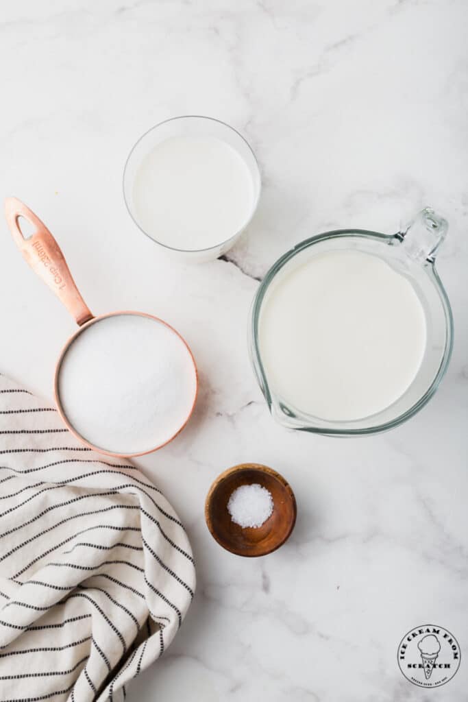 Ingredients needed for sweet cream ice cream, in separate bowls on a marble counter.