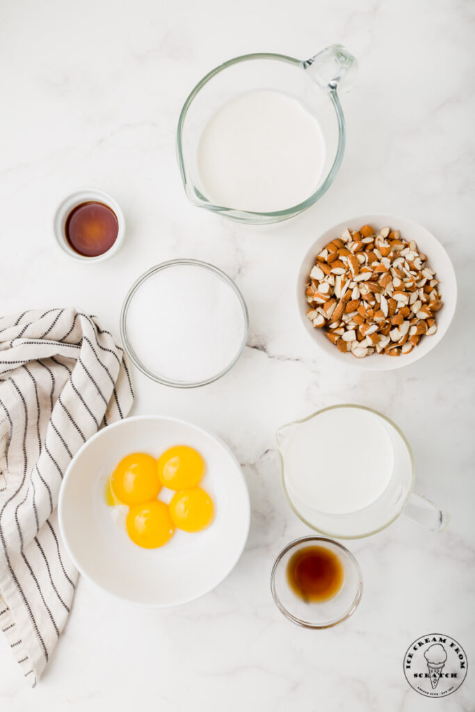 Ingredients for Toasted almond ice cream, each in separate bowls on a marble countertop