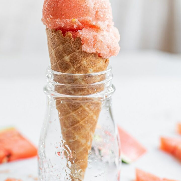 a scoop of watermelon sorbet in an ice cream cone, in a jar
