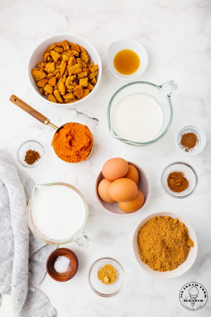 top down view of all of the ingredient needed to make pumpkin pie ice cream, each in separate white and glass bowls, all set on a marble countertop