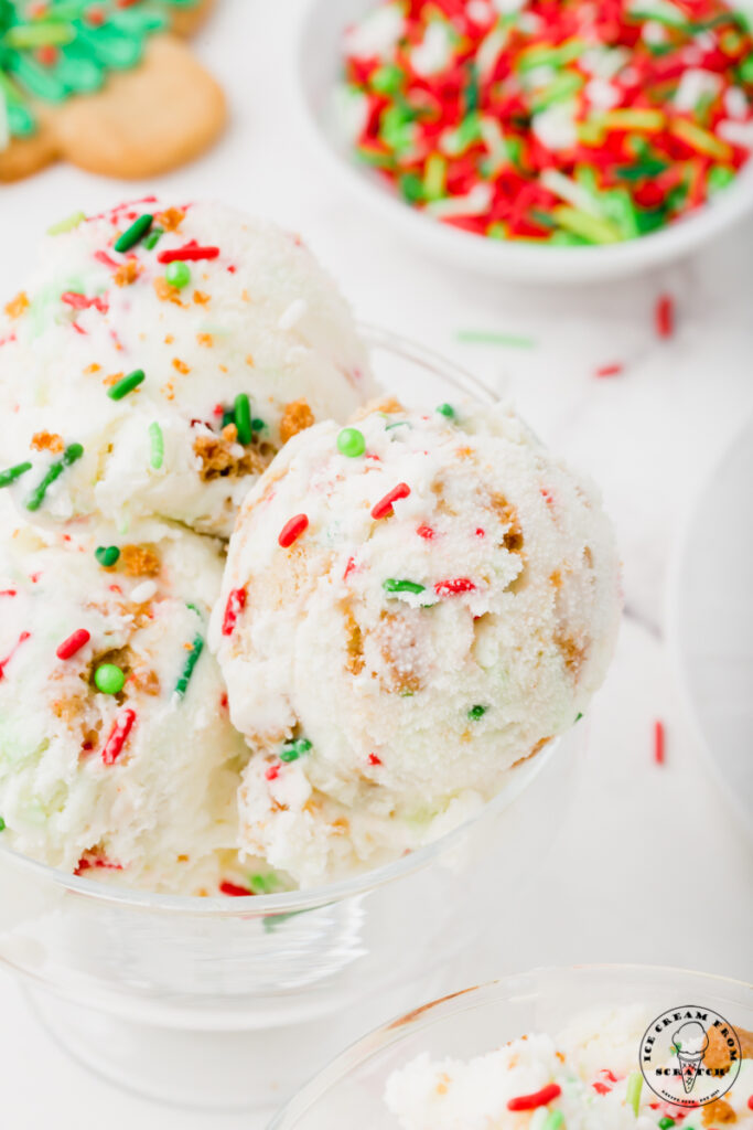 closeup view of a dish of ice cream with christmas sprinkles and christmas cookies inside. 