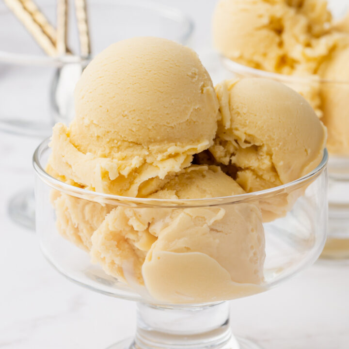 a footed glass dish with smooth sides, filled with four scoops of oat milk ice cream.