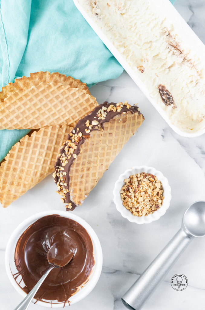 top down view of a choco taco next to melted chocolate and chopped nuts