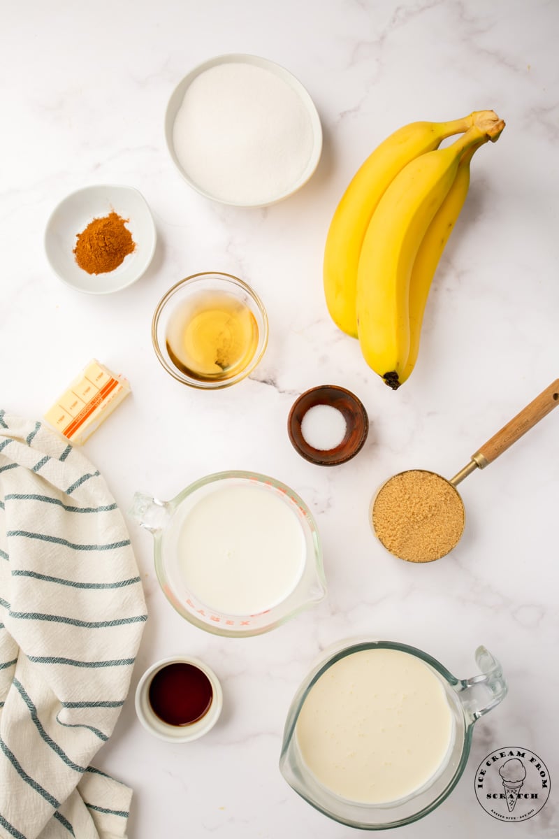 The ingredients needed to make banana foster ice cream, all in seperate bowls on a marble counter, viewed from above