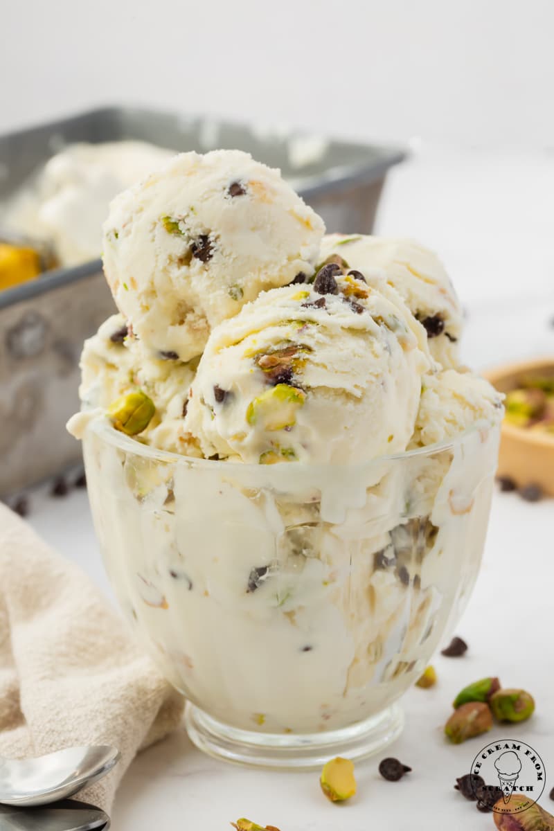 cannoli ice cream with chopped pistachios and chocolate chips in a glass dessert dish.