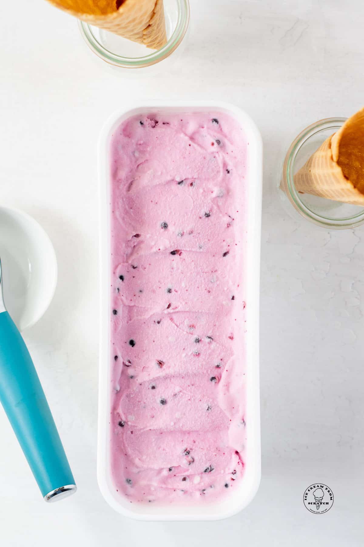 a long white ice cream container filled with light purple huckleberry ice cream.