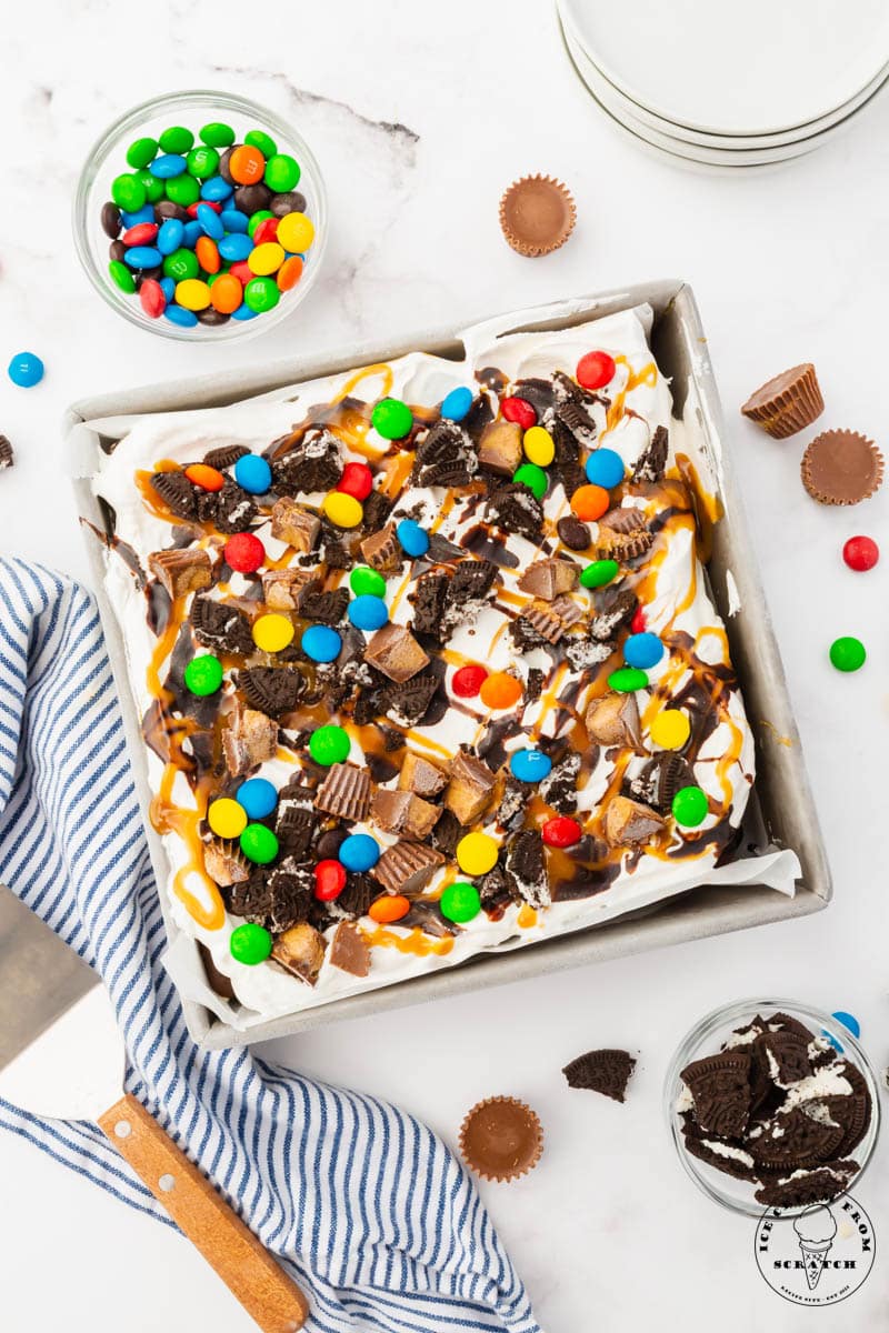 top down view of an ice crema sandwich cake topped with whipped cream and various sundae toppings.