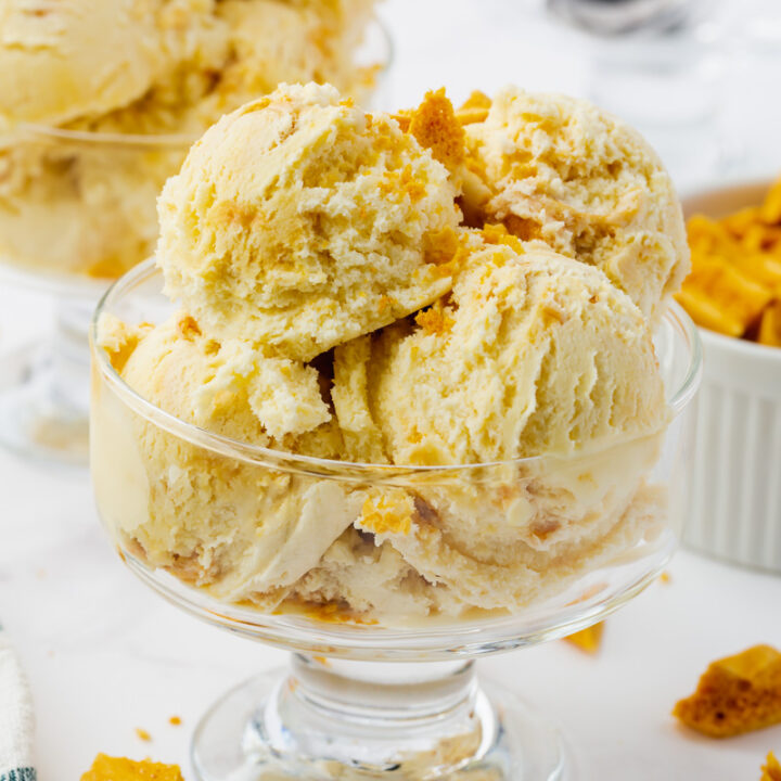 homemade ice cream with honeycomb toffee pieces, scooped into a footed glass ice cream dish.