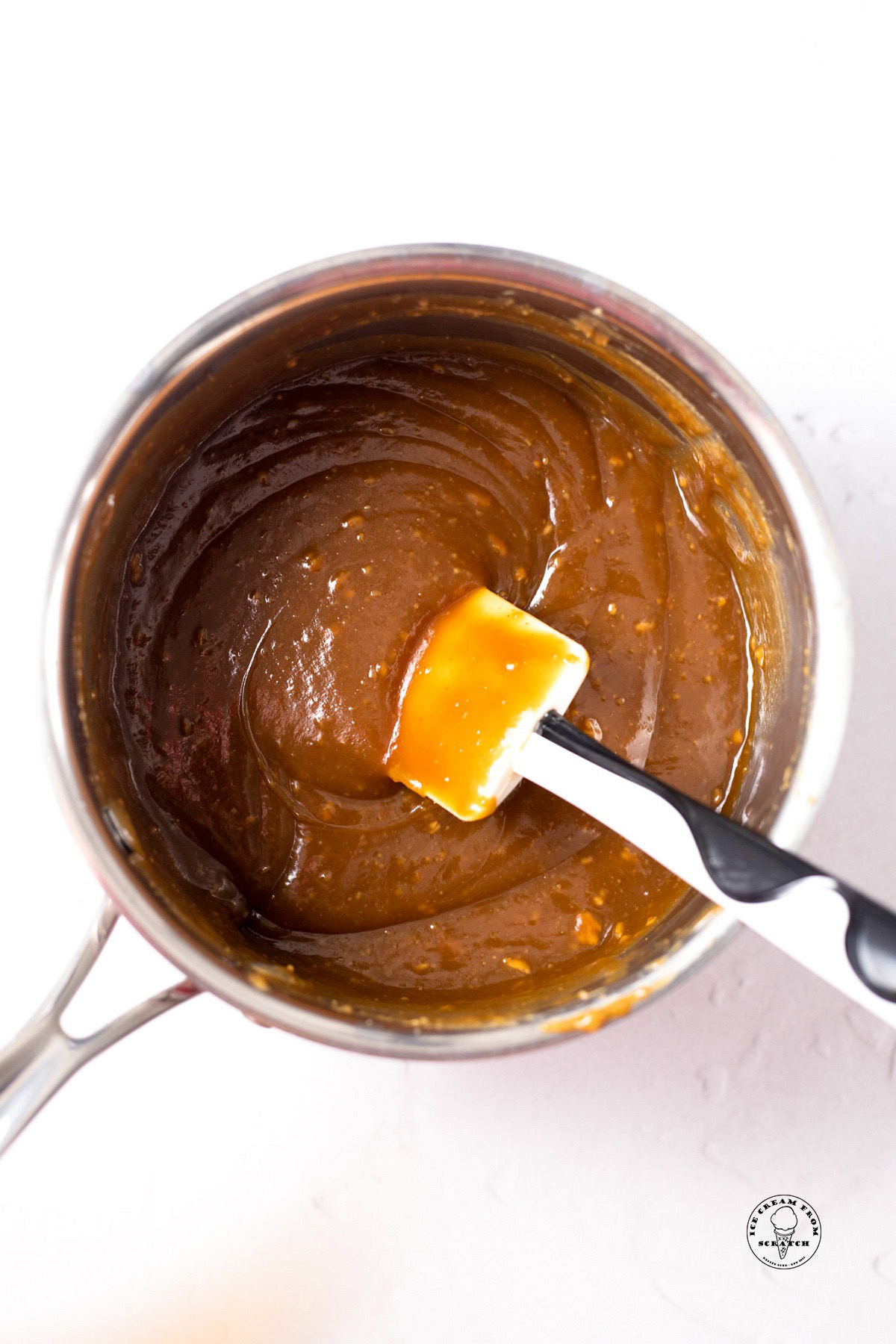 a small saucepan cooking down ingredients to make peanut butter sauce for ice cream. There is a rubber spatula in the pot.