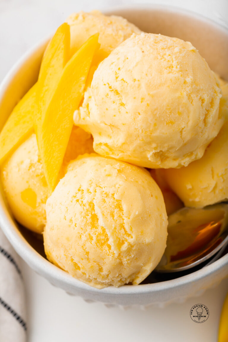 a bowl filled with scoops of mango gelato and mango slices.