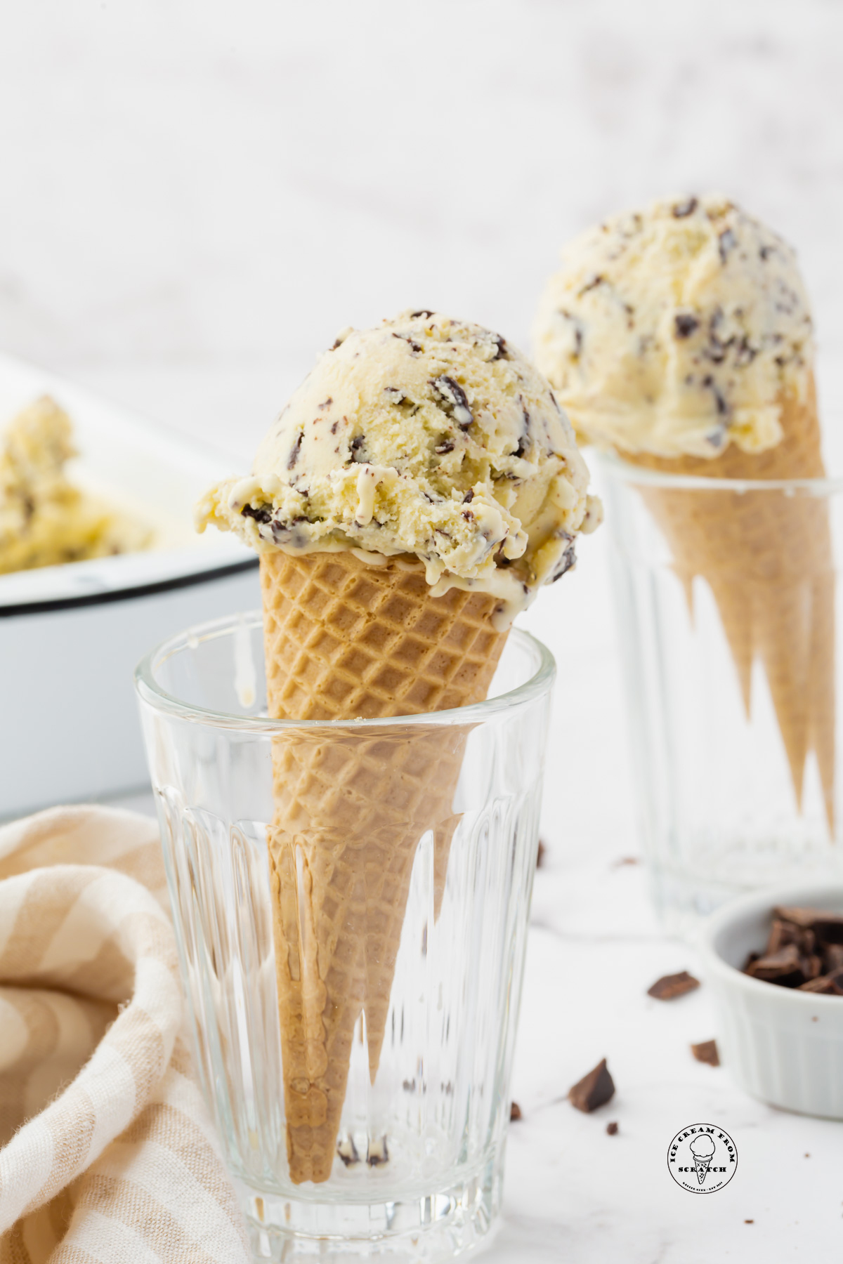two sugar cones topped with stracciatella gelato, propped up in juice glasses.