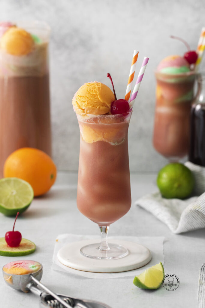 A tall hurricane glass of fruit punch with sherbet.