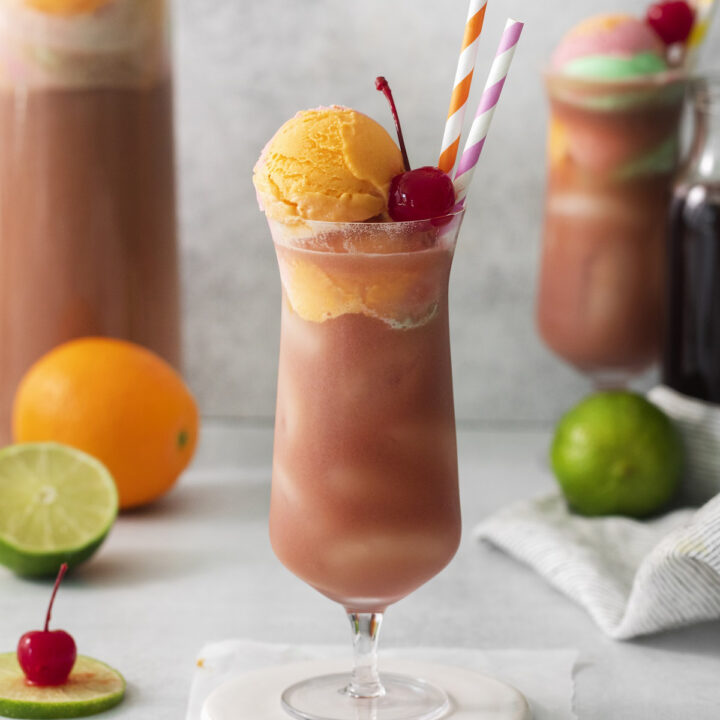 A tall hurricane glass of fruit punch with sherbet.