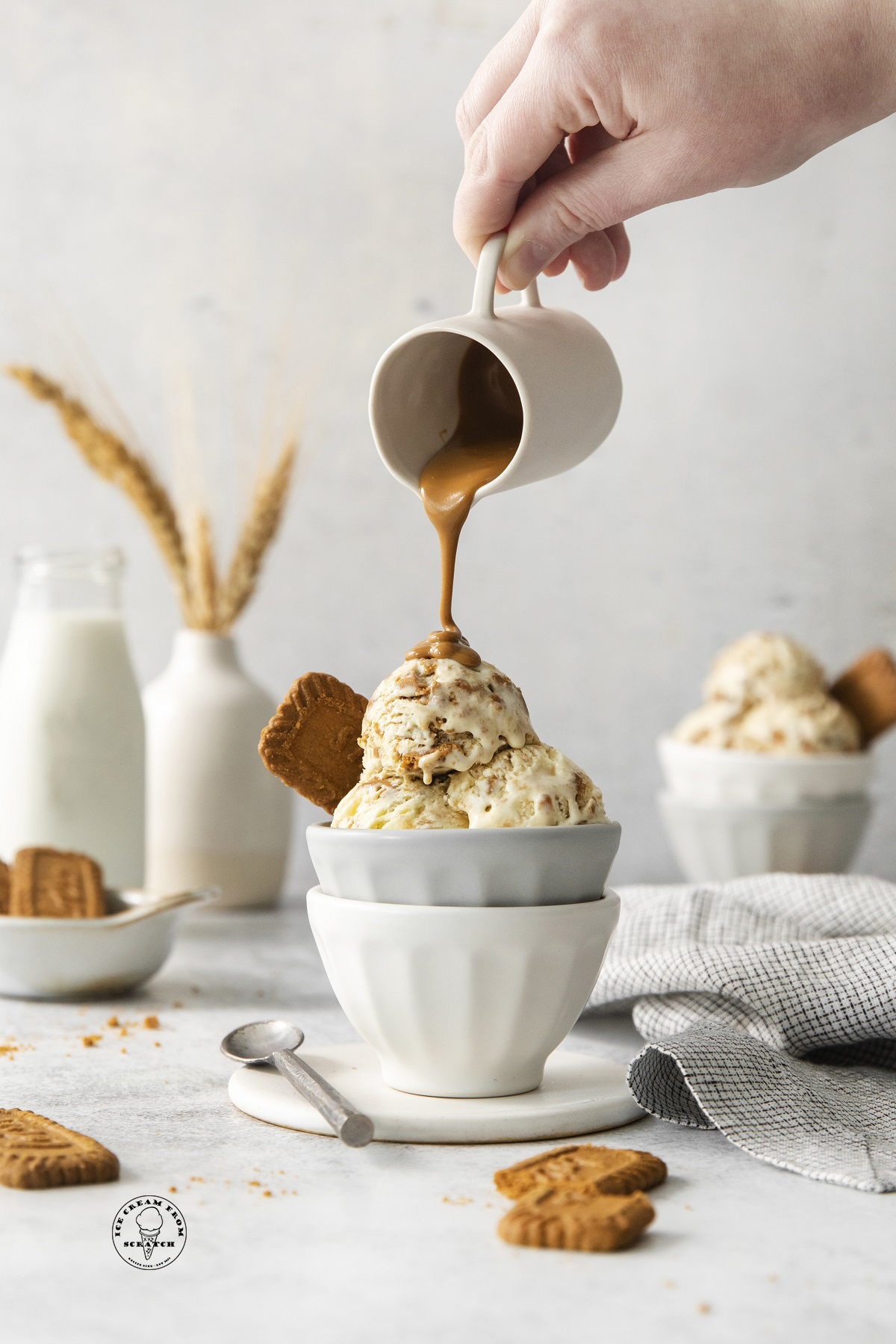 melted cookie butter being poured over a dish of homemade biscoff ice cream.