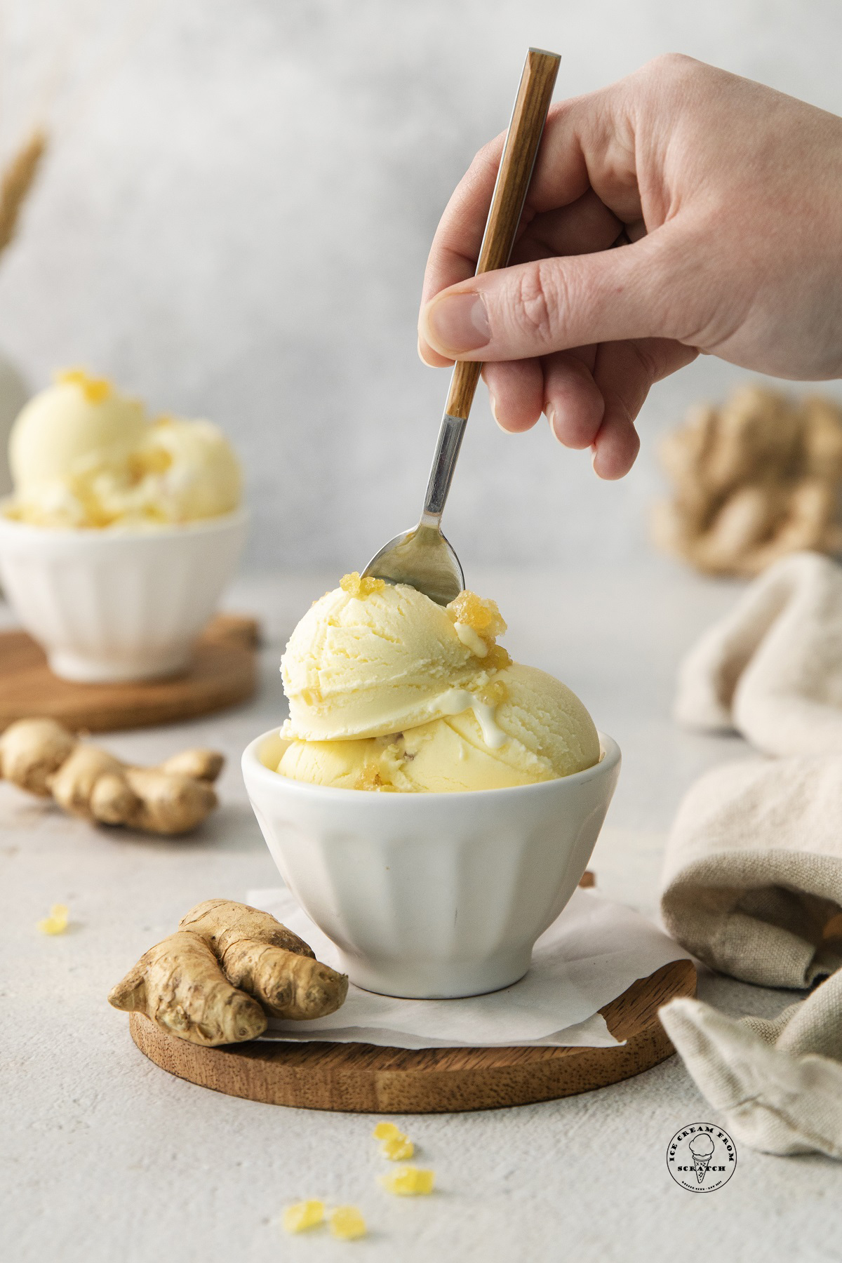 a hand with a spoon eating a bowl of ginger ice cream.