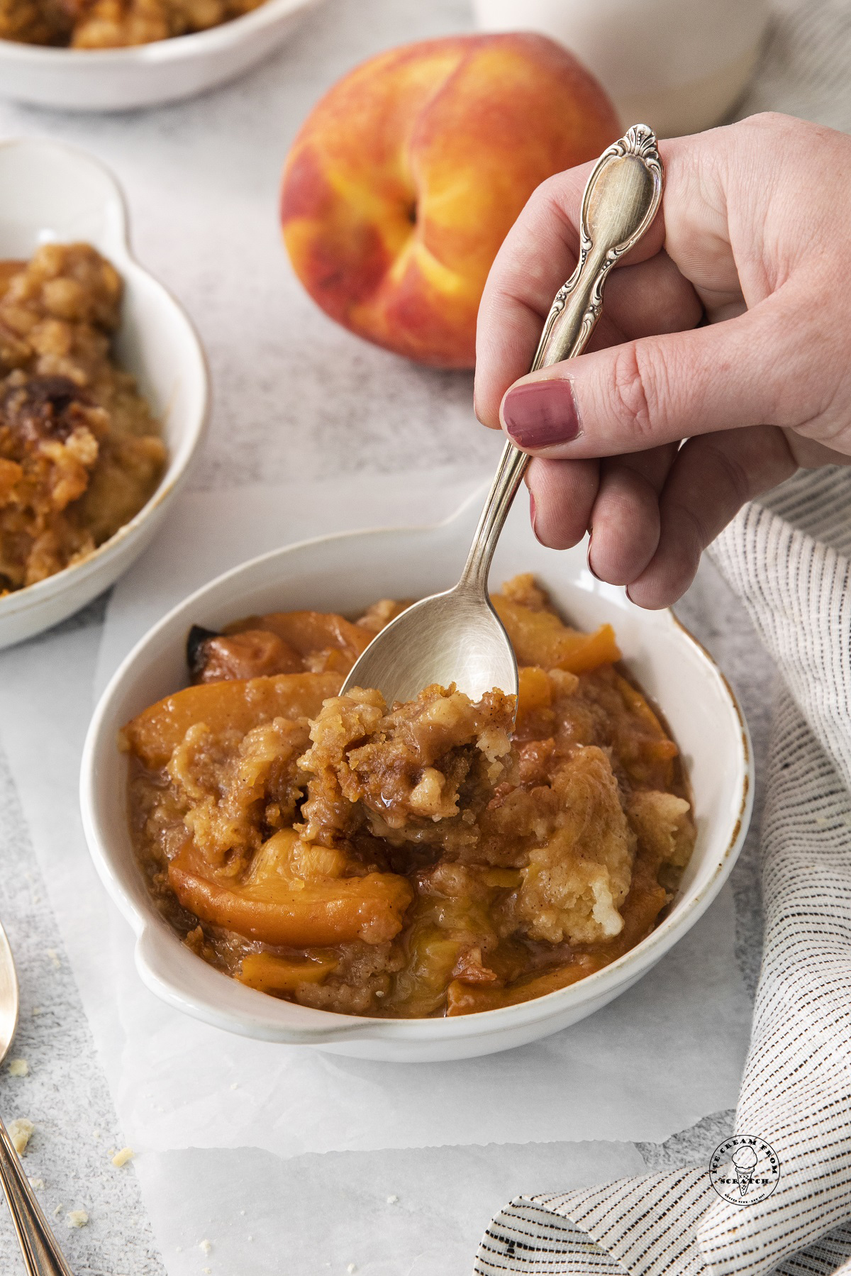a serving of peach cobber being enjoyed with a spoon.