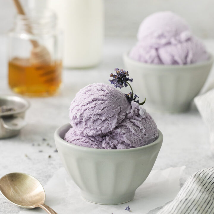 a small dish of scoops of lavender ice cream with flowers as garnish.