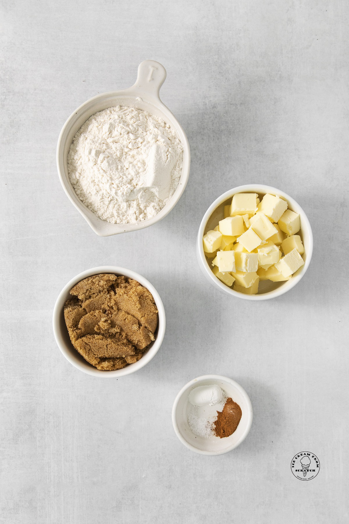 The ingredients for strawberry crumble topping, flour, butter, brown sugar, cinnamon, baking powder, salt, all in separate bowls.