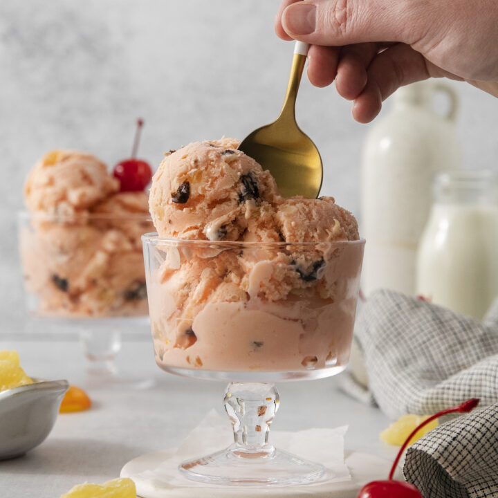 a hand holding a gold toned spoon in a dish of homemade tutti frutti ice cream