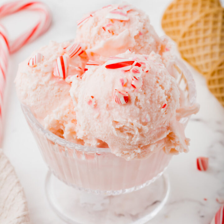 a bowl of pink candy cane ice cream topped with crushed candy cane pieces