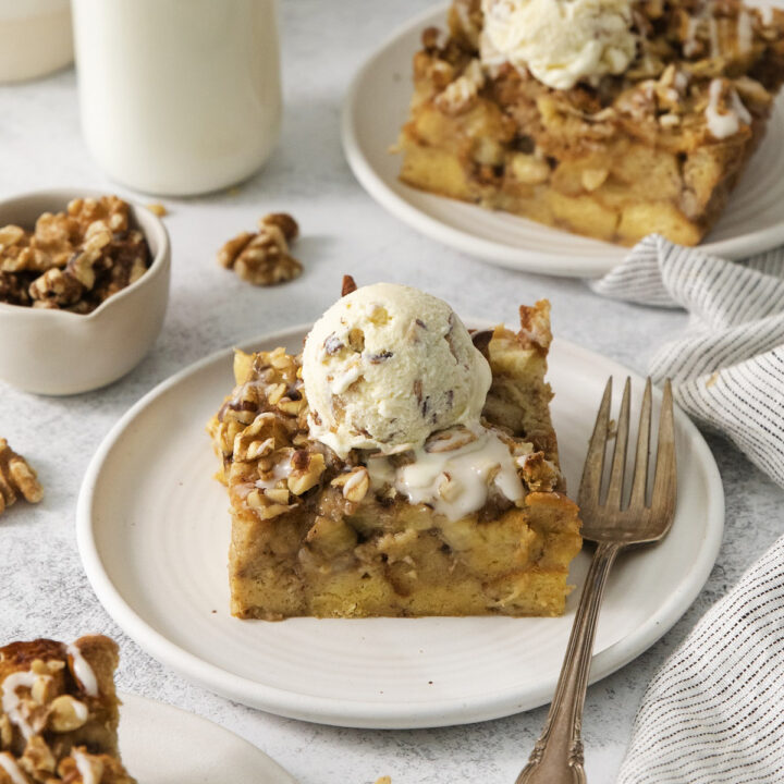 squares of Bread pudding made with bananas and nuts on dessert plates topped with ice cream