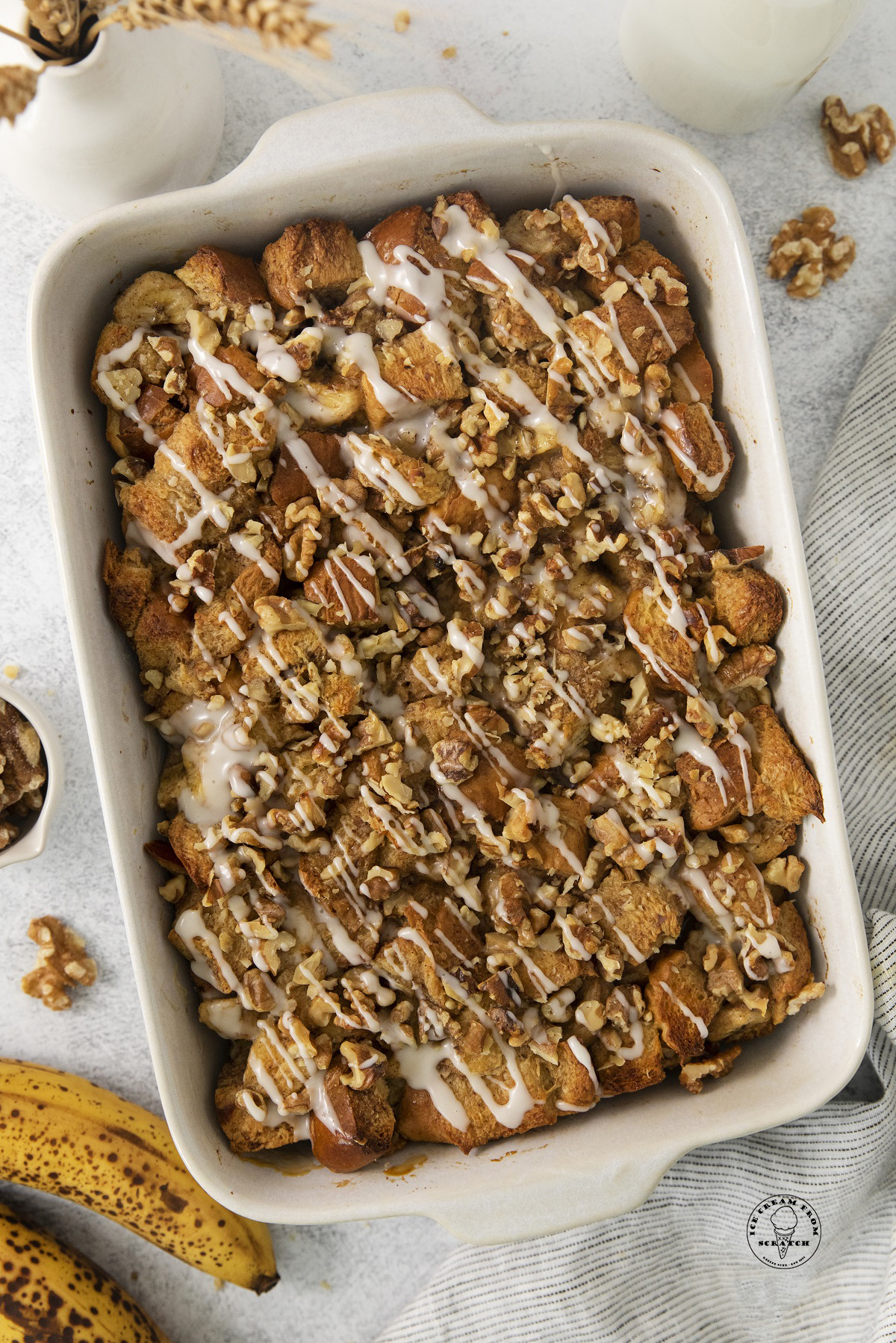 banana bread pudding in a white ceramic baking dish drizzled with vanilla rum glaze.