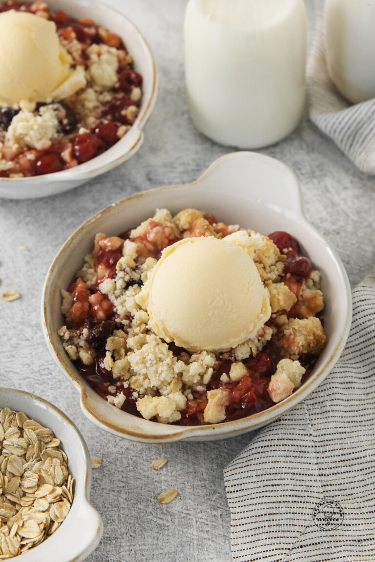 a bowl of cherry cobbler topped with vanilla ice cream.