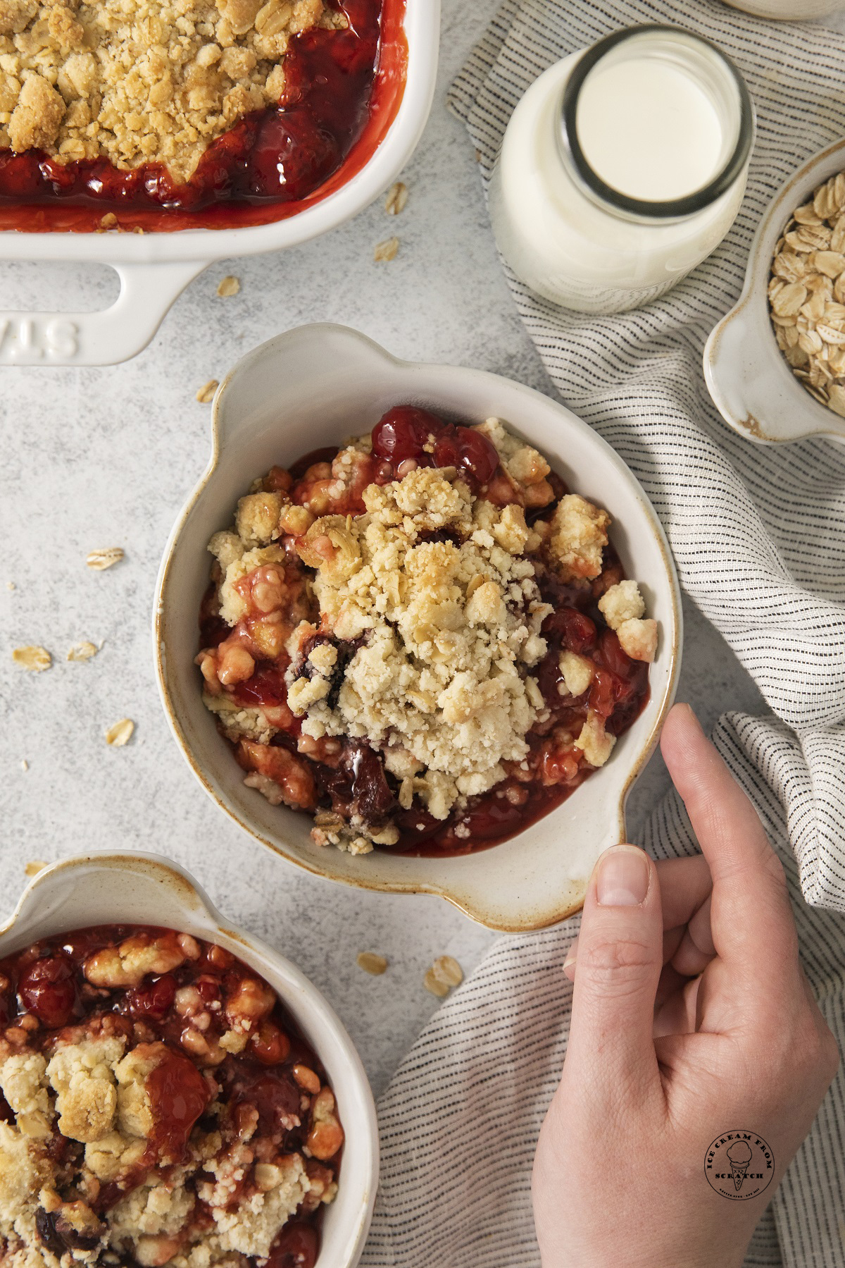 a hand grabbing a bowl of cake mix cherry cobbler.