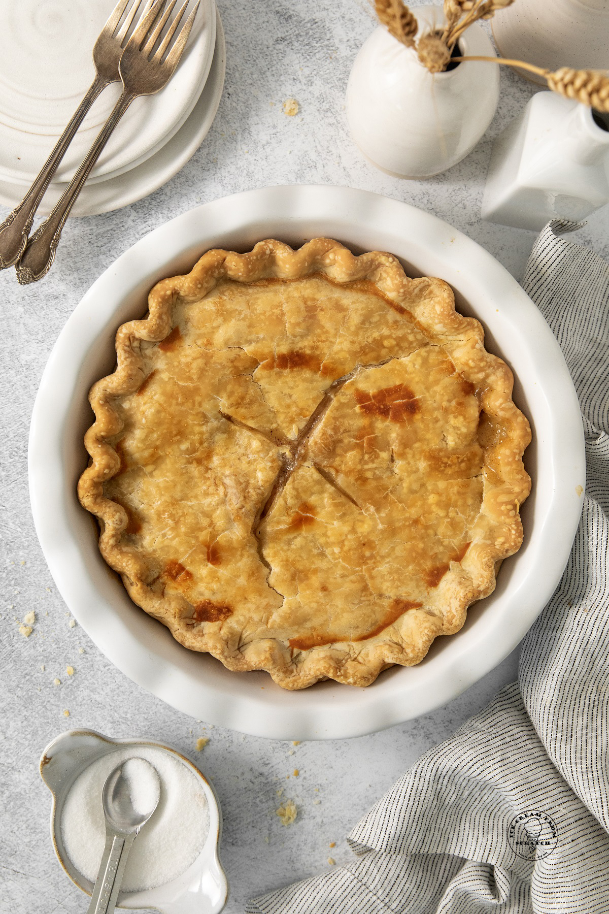 a baked peach pie in a white ceramic pie dish, viewed from above.