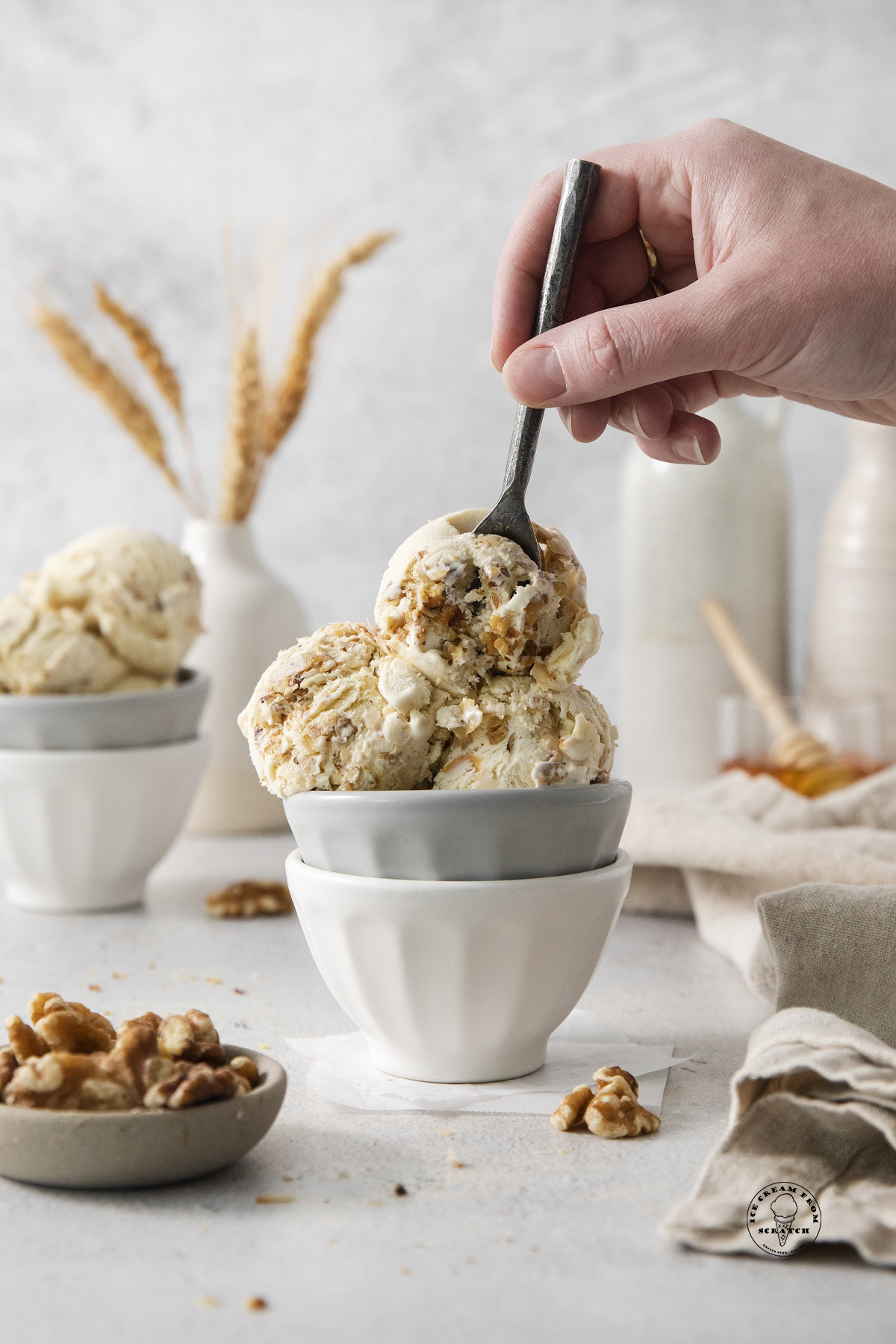 a hand holding a spoon, eating a bowl of homemade baklava ice cream.
