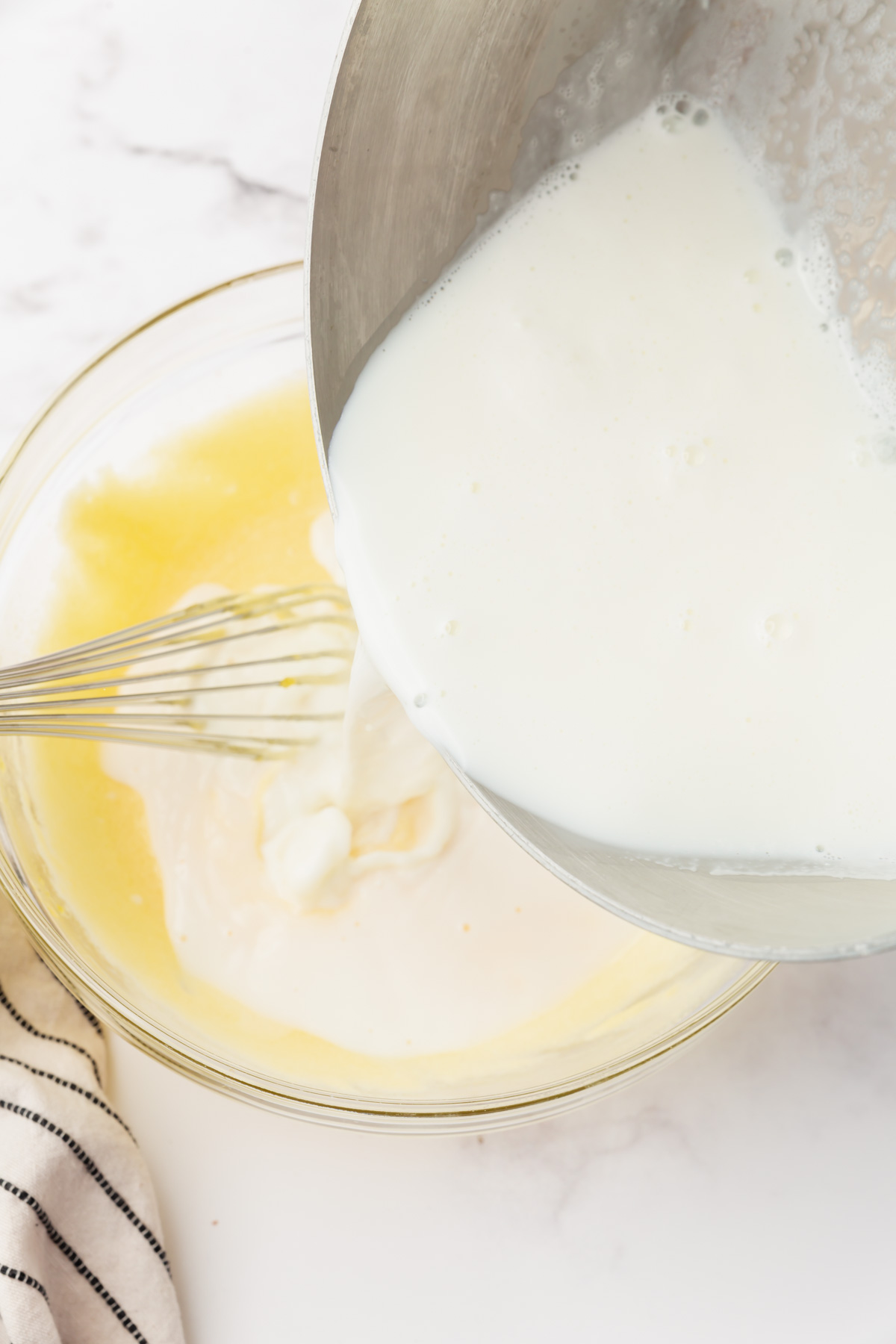 pouring warm milk into the egg mixture to tempure